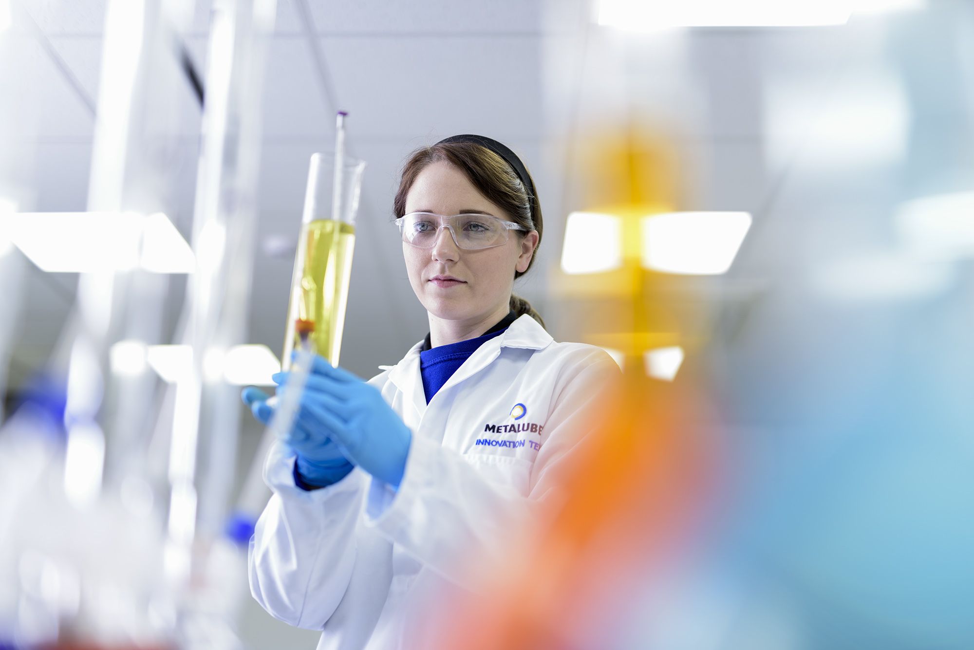 Woman in lab holding test tube full of industrial lubricant